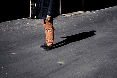 Eine Person steht alleine auf der Straße und wirft einen Schatten